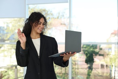 Portrait of young woman with laptop wearing stylish suit indoors