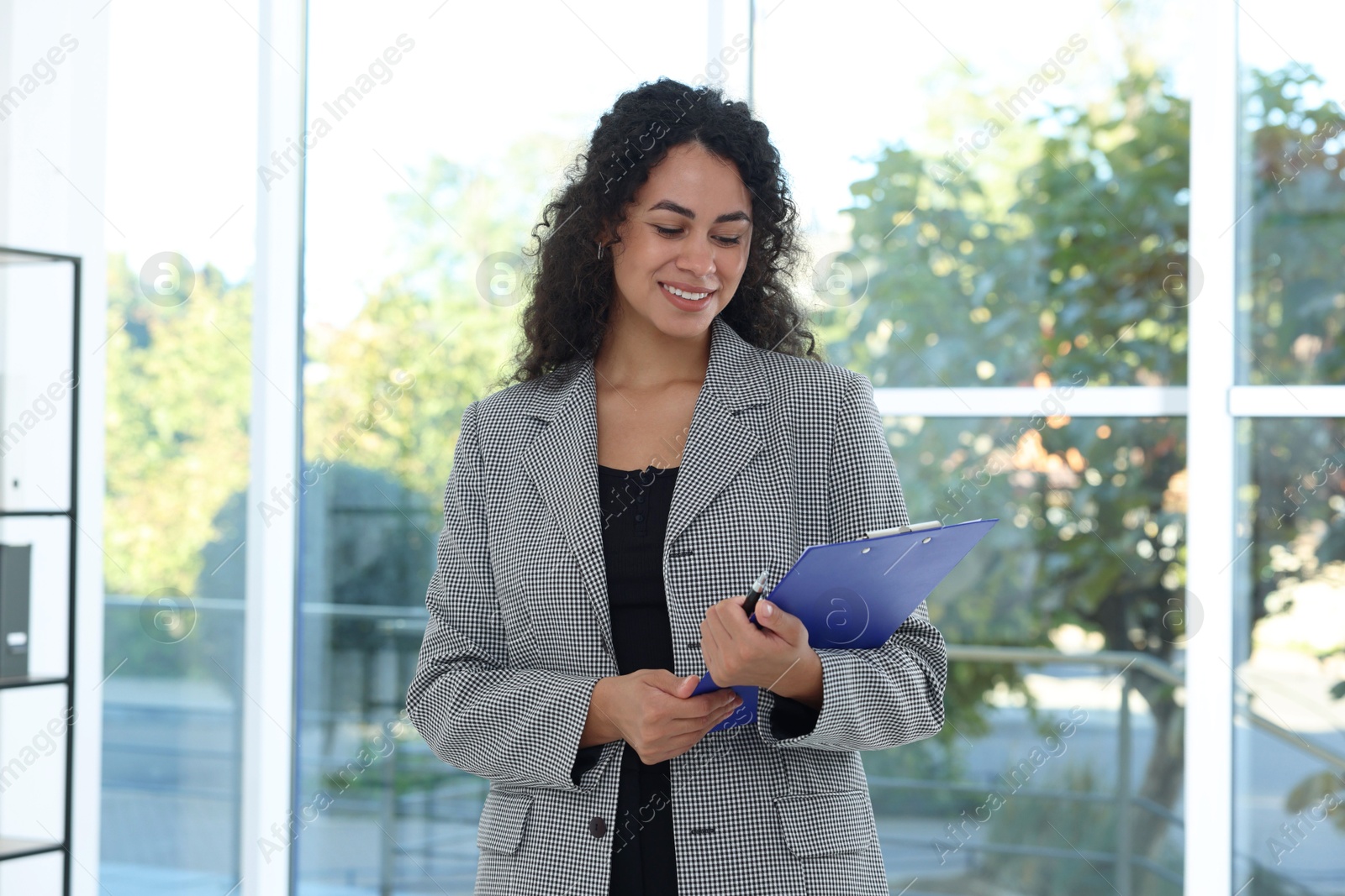 Photo of Portrait of young woman with clipboard wearing stylish suit indoors