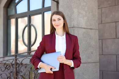 Photo of Portrait of young woman with laptop wearing stylish suit outdoors