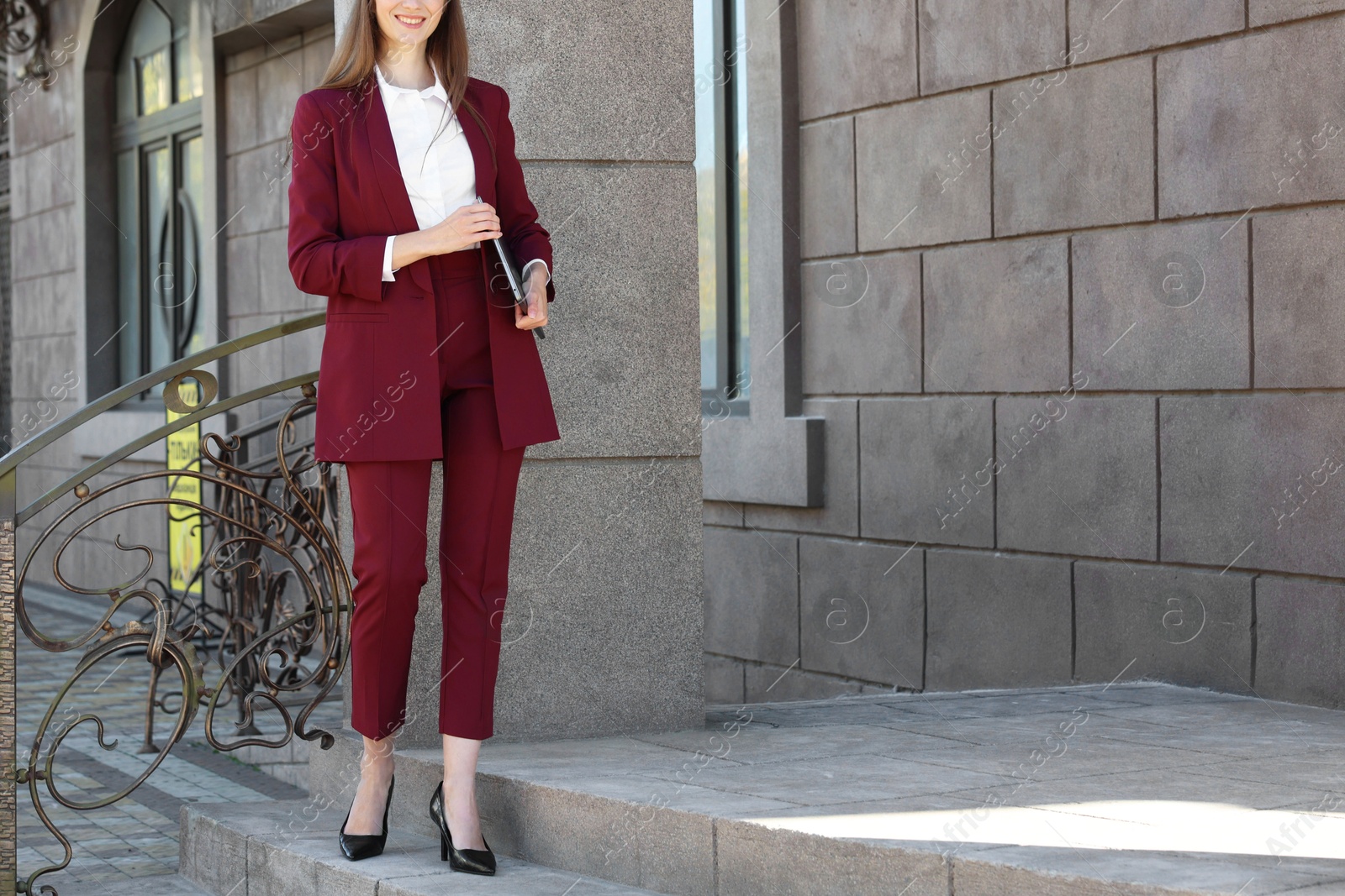 Photo of Young woman with laptop wearing stylish suit outdoors, closeup. Space for text