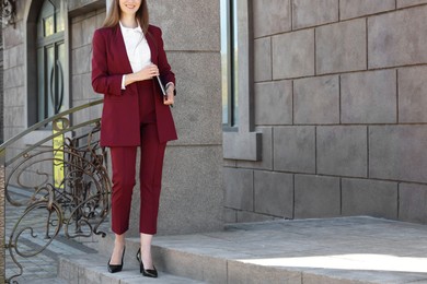 Photo of Young woman with laptop wearing stylish suit outdoors, closeup. Space for text