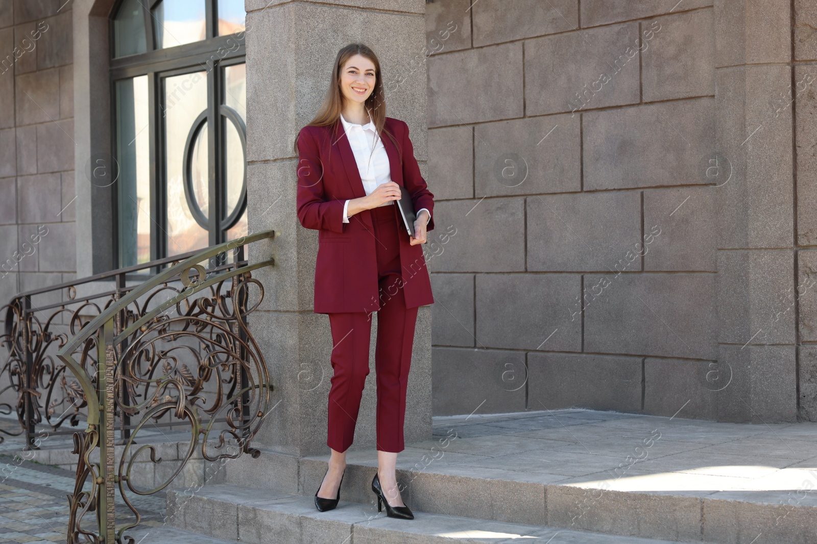 Photo of Portrait of young woman with laptop wearing stylish suit outdoors. Space for text