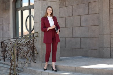 Photo of Portrait of young woman with laptop wearing stylish suit outdoors. Space for text