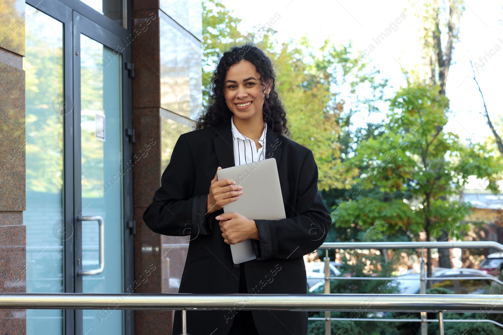 Photo of Portrait of young woman with laptop wearing stylish suit outdoors