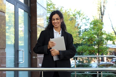 Portrait of young woman with laptop wearing stylish suit outdoors