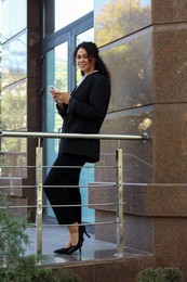 Photo of Portrait of young woman with phone wearing stylish suit outdoors