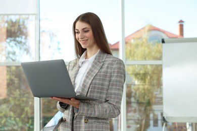 Photo of Portrait of young woman with laptop wearing stylish suit indoors