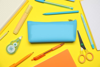 Photo of Pencil case and different stationery on yellow background, flat lay