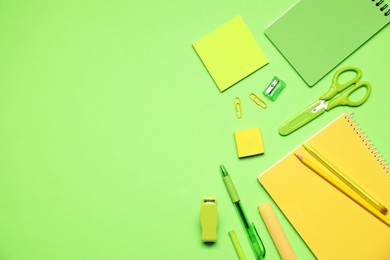 Photo of Different stationery on green background, flat lay. Space for text
