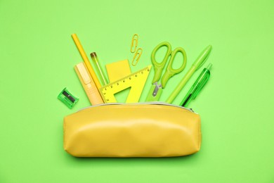 Photo of Pencil case and different stationery on green background, flat lay