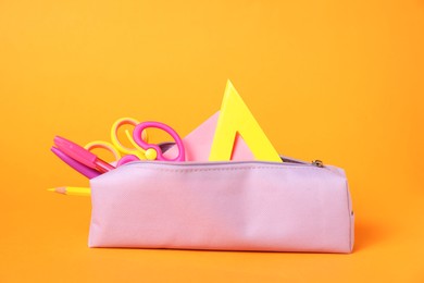 Photo of Different stationery in pencil case on orange background