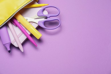 Photo of Pencil case with different stationery on purple background, flat lay. Space for text