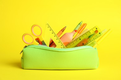 Photo of Different stationery in pencil case on yellow background