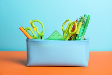 Photo of Different stationery in pencil case on color background