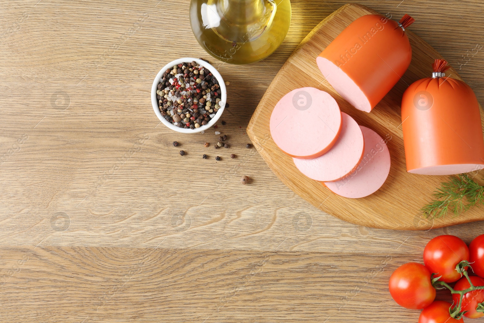 Photo of Tasty boiled sausages, spices and tomatoes on wooden table, top view. Space for text