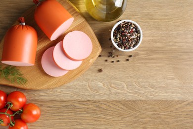 Photo of Tasty boiled sausages, spices and tomatoes on wooden table, top view. Space for text