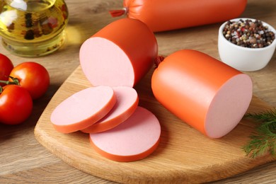 Photo of Tasty boiled sausages, spices and tomatoes on wooden table, closeup