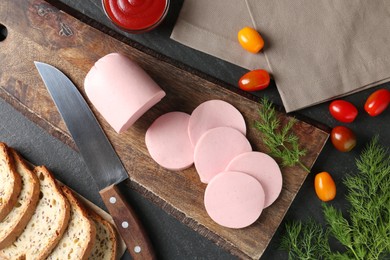 Photo of Tasty boiled sausage, knife, tomatoes, dill, bread and ketchup on black table, top view