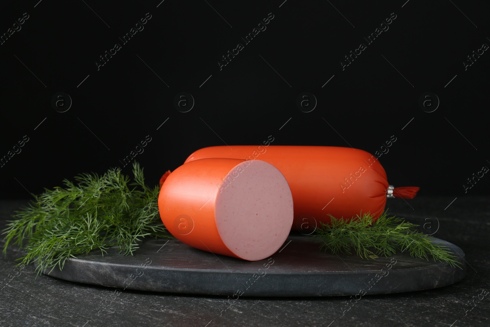 Photo of Tasty boiled sausages and dill on black table