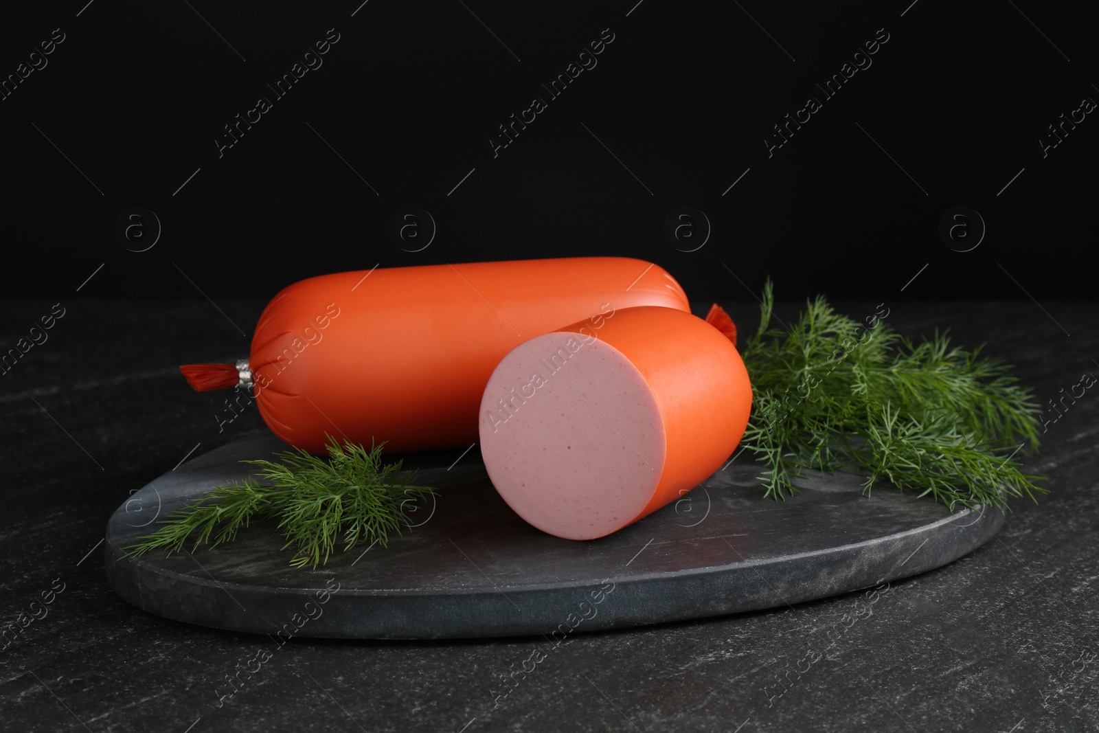 Photo of Tasty boiled sausages and dill on black table