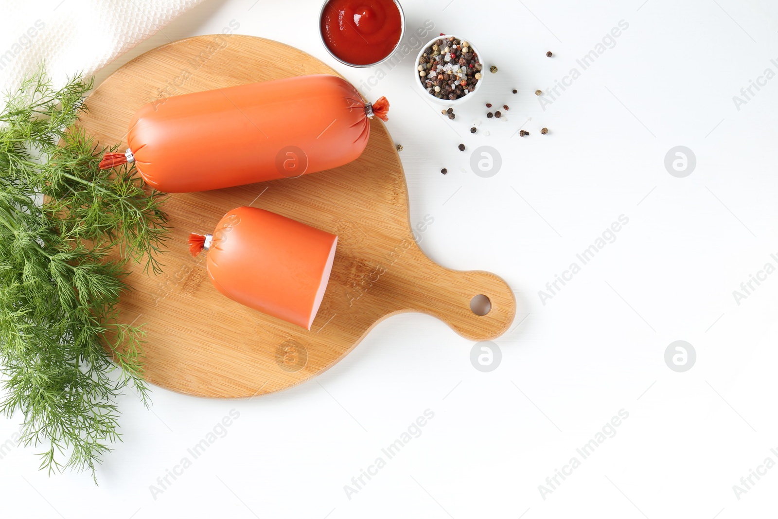 Photo of Tasty boiled sausages, ketchup and spices on white table, top view. Space for text