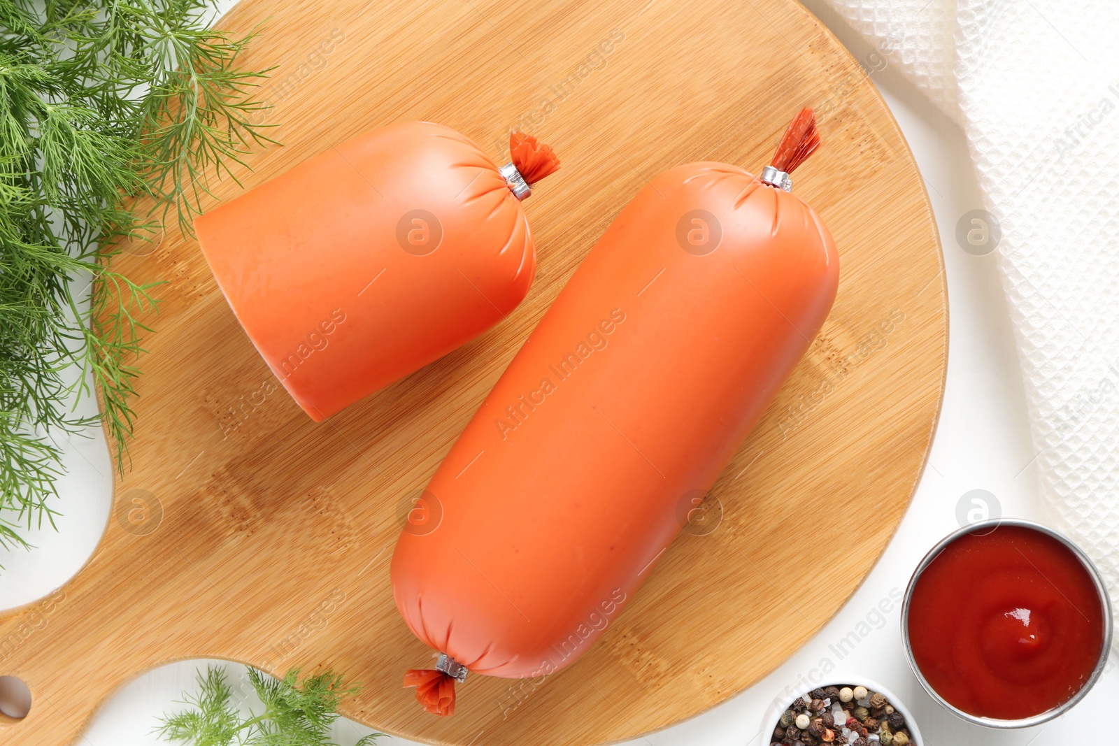 Photo of Tasty boiled sausages, ketchup and spices on white table, top view