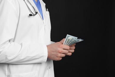 Photo of Corruption concept. Doctor with dollar banknotes on black background, closeup