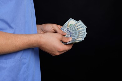 Photo of Corruption concept. Doctor with dollar banknotes on black background, closeup