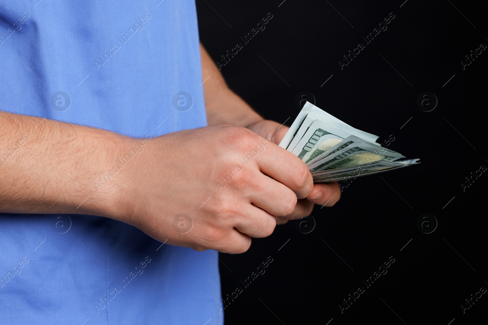 Photo of Corruption concept. Doctor with dollar banknotes on black background, closeup