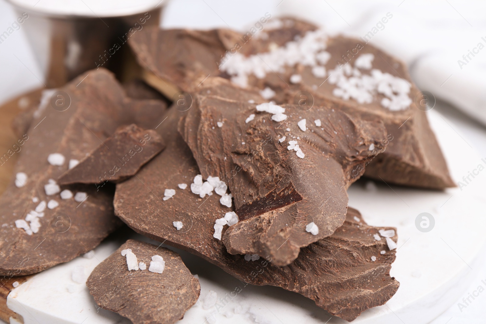 Photo of Pieces of tasty chocolate with salt on white table, closeup