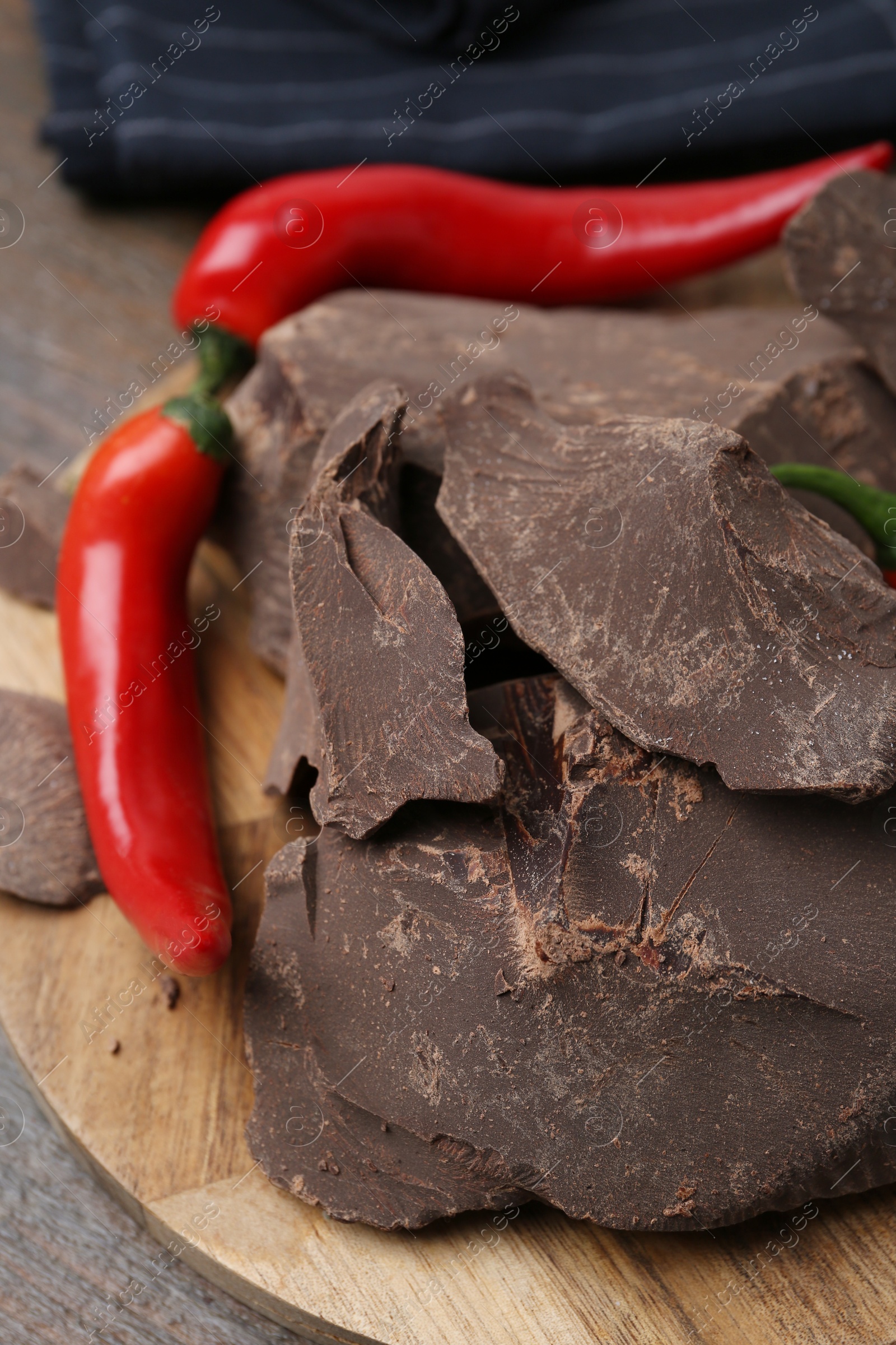 Photo of Pieces of tasty chocolate with chili peppers on table, closeup