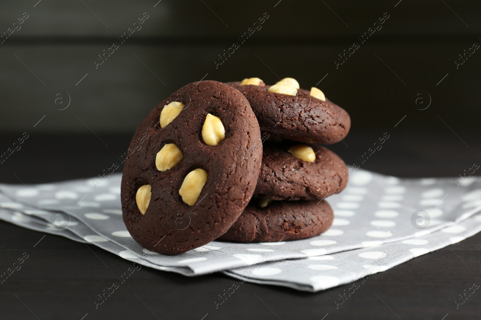 Photo of Delicious chocolate cookies with hazelnuts on black wooden table, closeup