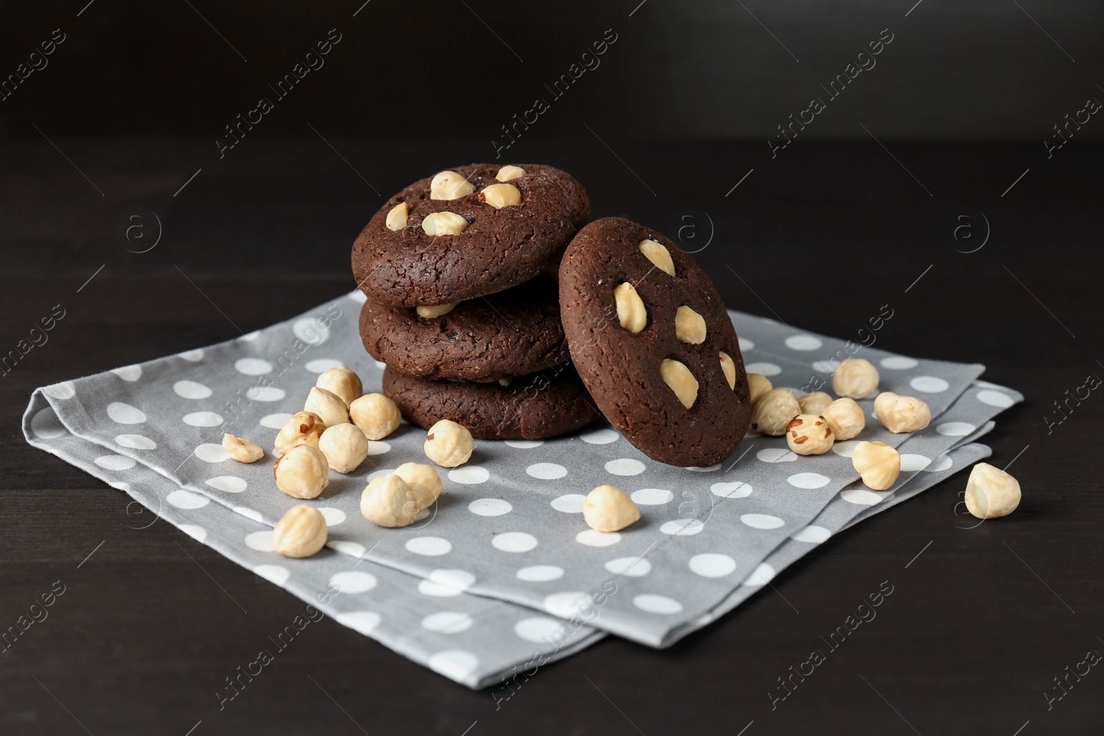 Photo of Delicious chocolate cookies with hazelnuts on black wooden table, closeup