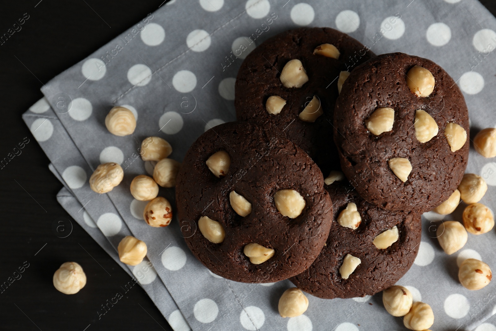 Photo of Delicious chocolate cookies with hazelnuts on black table, top view