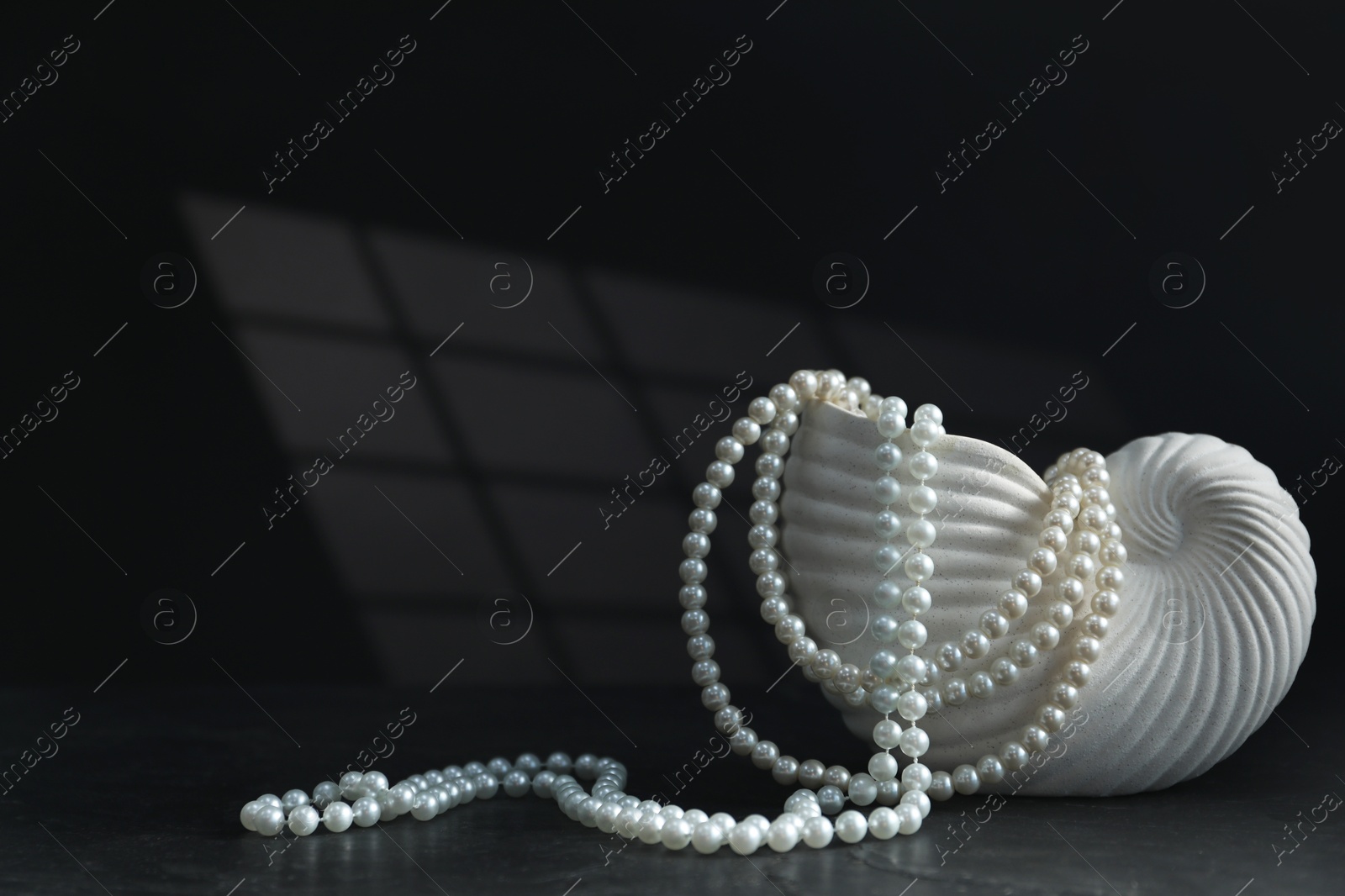 Photo of Stylish vase and elegant pearl jewelry on black background, space for text