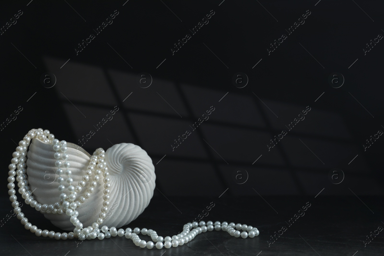 Photo of Stylish vase and elegant pearl jewelry on black background, space for text