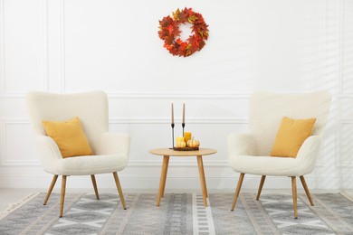 Photo of Soft armchairs, coffee table and autumn decor in room