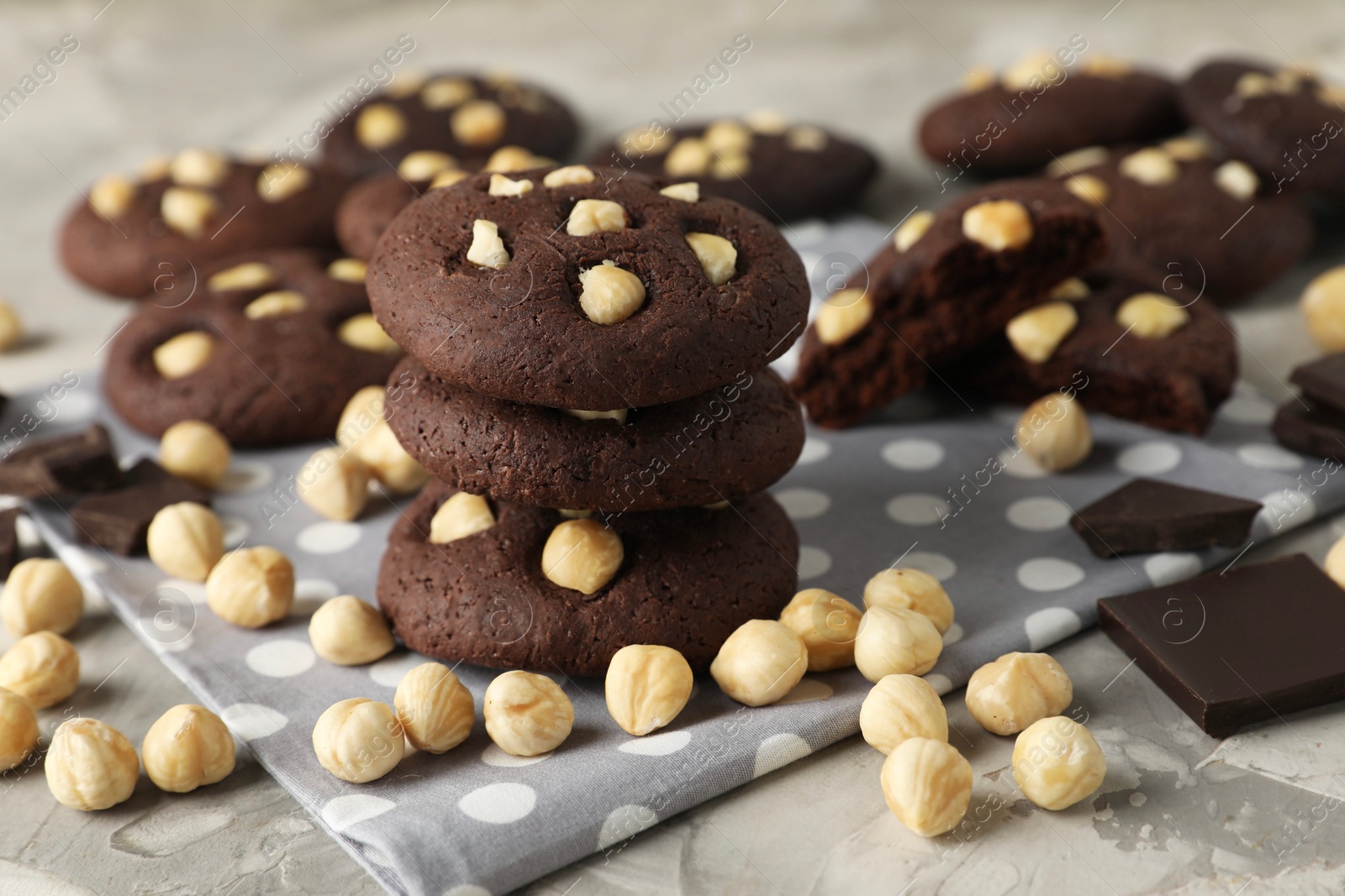 Photo of Tasty chocolate cookies with hazelnuts on grey table, closeup