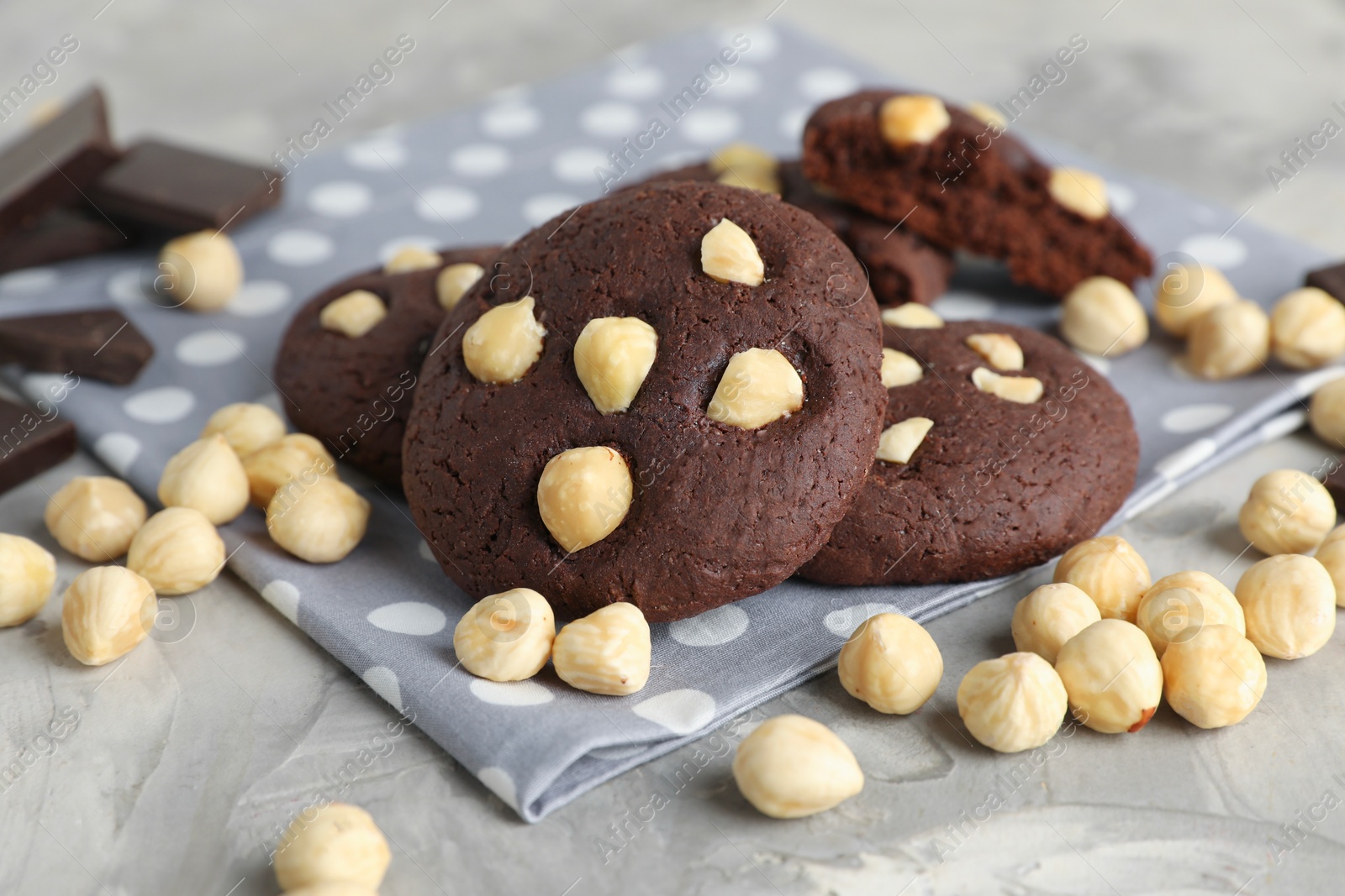 Photo of Tasty chocolate cookies with hazelnuts on grey table, closeup