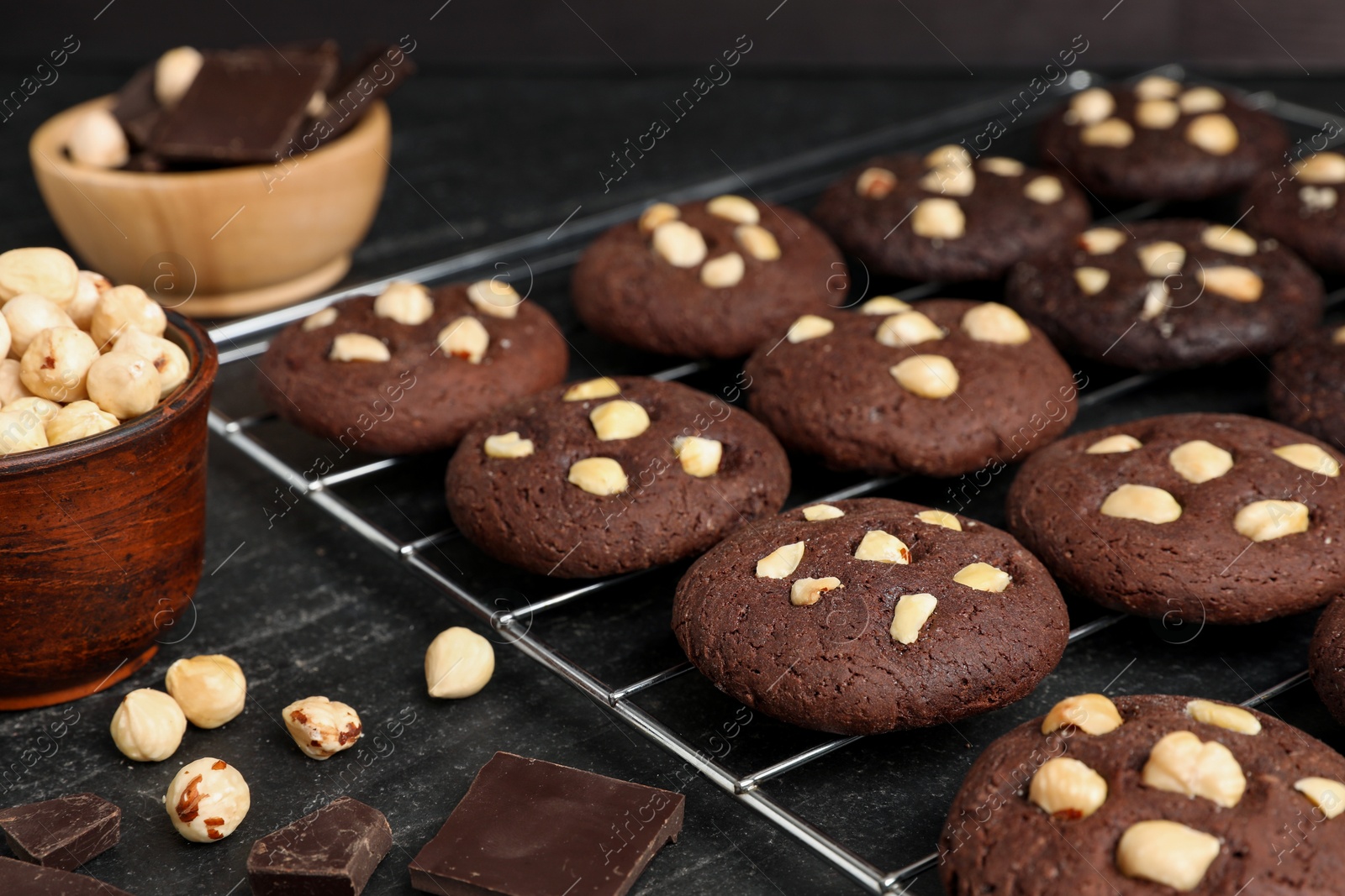 Photo of Tasty chocolate cookies with hazelnuts on black table, closeup