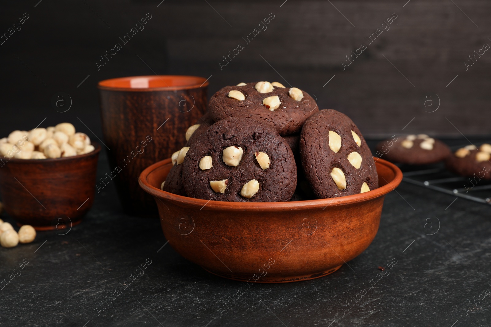 Photo of Tasty chocolate cookies with hazelnuts on black table, closeup