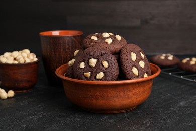 Photo of Tasty chocolate cookies with hazelnuts on black table, closeup