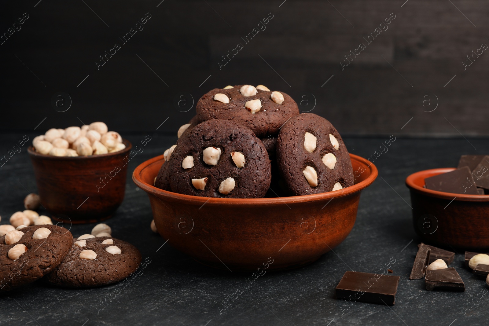 Photo of Tasty chocolate cookies with hazelnuts on black table