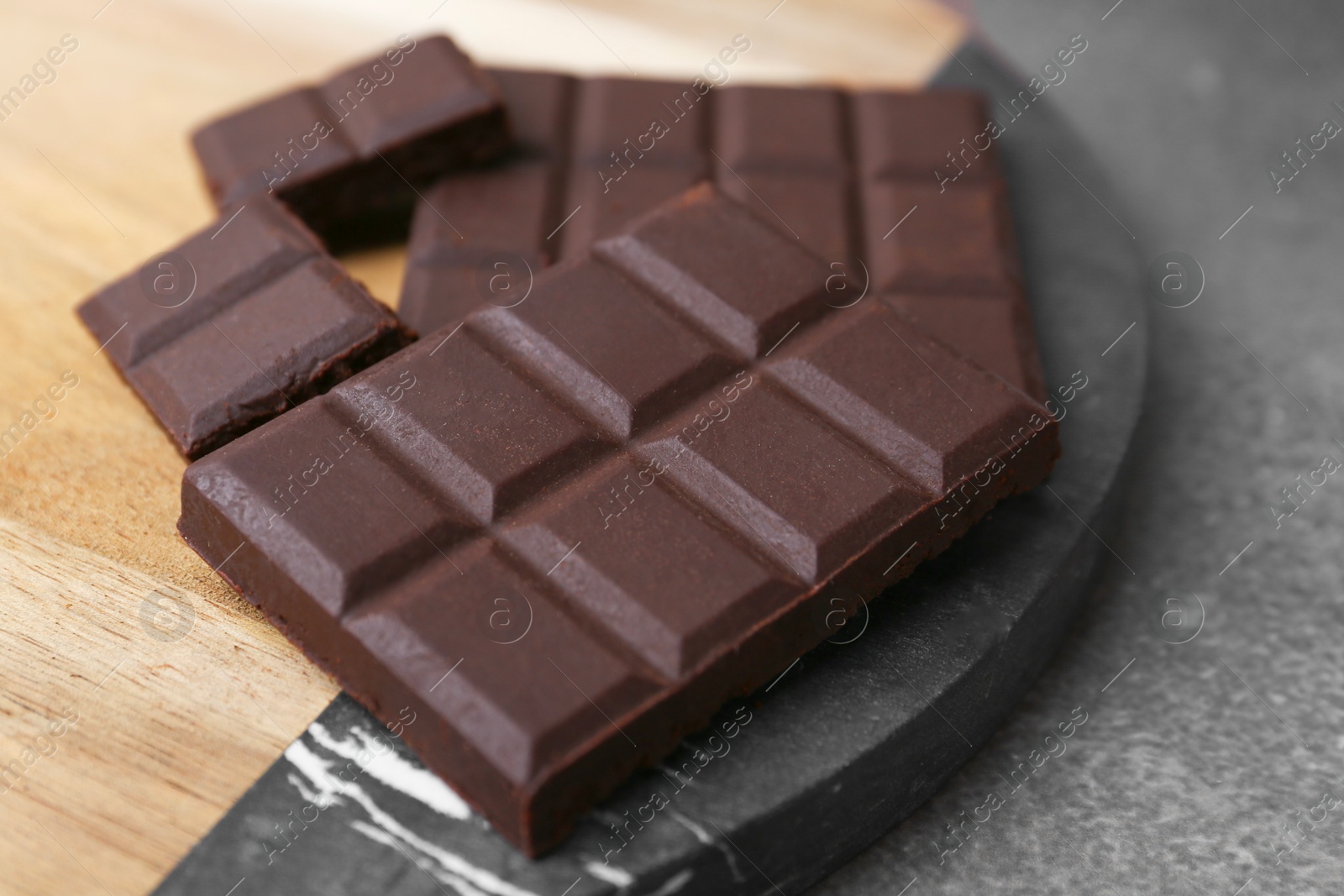 Photo of Pieces of delicious dark chocolate on brown table, closeup