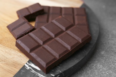 Photo of Pieces of delicious dark chocolate on brown table, closeup