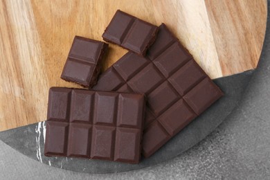 Pieces of delicious dark chocolate on brown table, top view