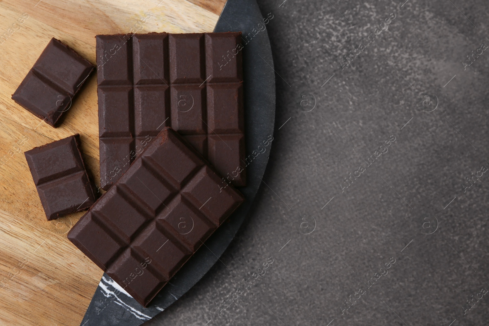 Photo of Pieces of delicious dark chocolate on brown table, top view. Space for text