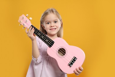 Photo of Little girl with ukulele on orange background