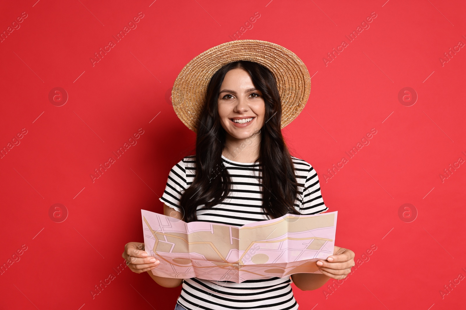 Photo of Young tourist in hat with map on red background