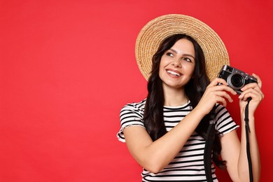 Photo of Young tourist in hat with camera on red background, space for text